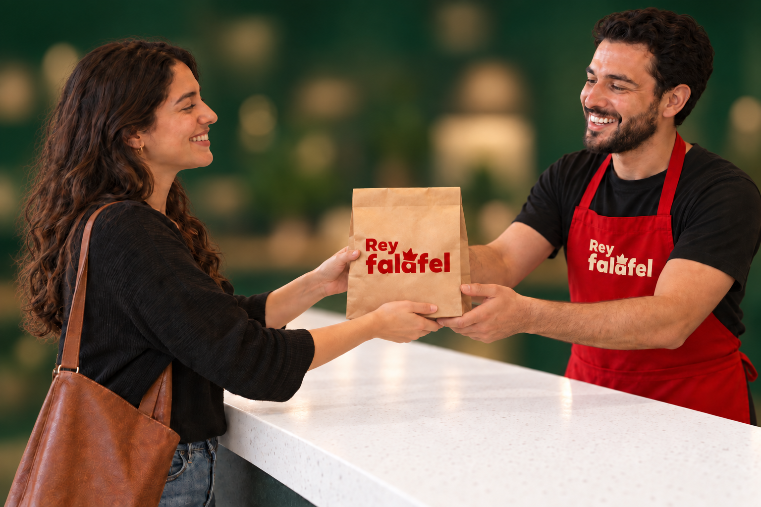 Escena ilustrativa de una clienta recibiendo una bolsa kraft con el logo rojo de Rey Falafel, de un colaborador con gavacha roja, sobre un mostrador de cuarzo blanco
